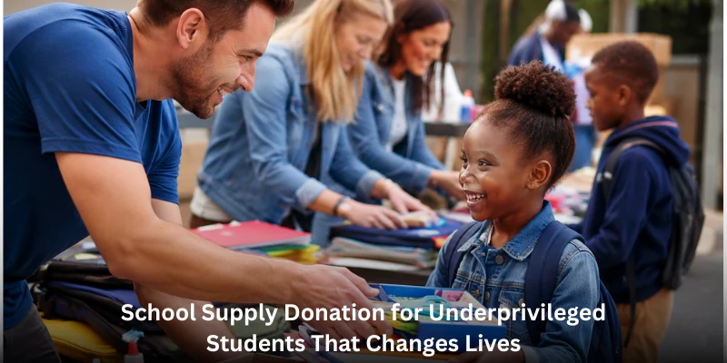 A friendly female volunteer smiling while handing a navy blue backpack filled with notebooks to a young boy at a school supply donation event.